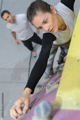 Foto Lady reaching to grip climbing hold on indoor wall