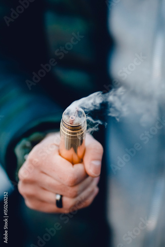 vaping man holding a mod device. cloud of vapor. Vape. Electric cigarettes