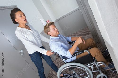 young girl helps a disabled to reach an elevator photo