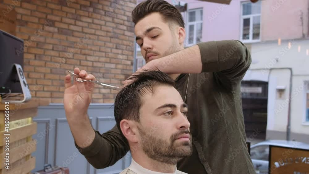 Man hairdresser doing haircut beard adult men in the men's hair salon. Haircut with scissors Man hairdresser doing haircut beard adult men in the men's hair salon. Haircut with scissors