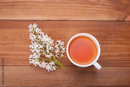 Cup of tea and a bouquet of lilacs on a wooden background.