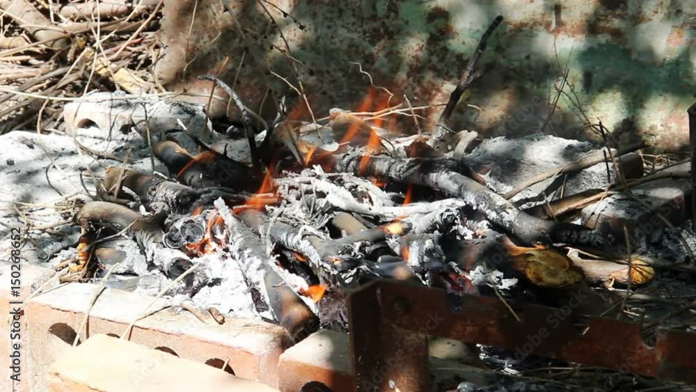 Firewood burns in a homemade brazier for a barbecue made of bricks and metal strips. Firewood burns in a homemade brazier for a barbecue made of bricks and metal strips.
