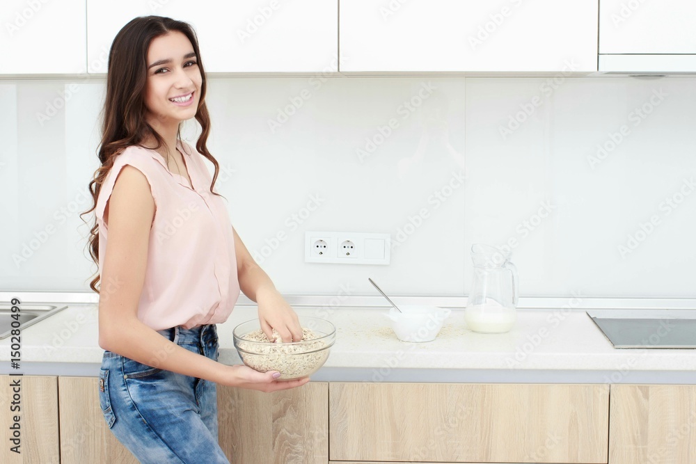 Healthy breakfast . Young beautiful cheerful woman putting cereal in a bowl while sitting on the worktop and smiling. Healthy breakfast . Young beautiful cheerful woman putting cereal in a bowl while sitting on the worktop and smiling.