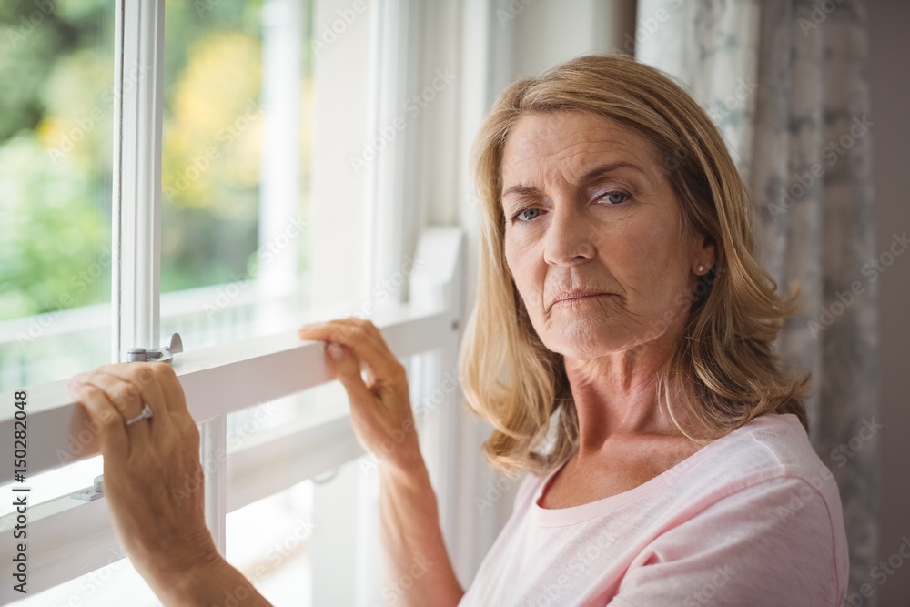 Portrait of senior woman standing next to window Portrait of senior woman standing next to window