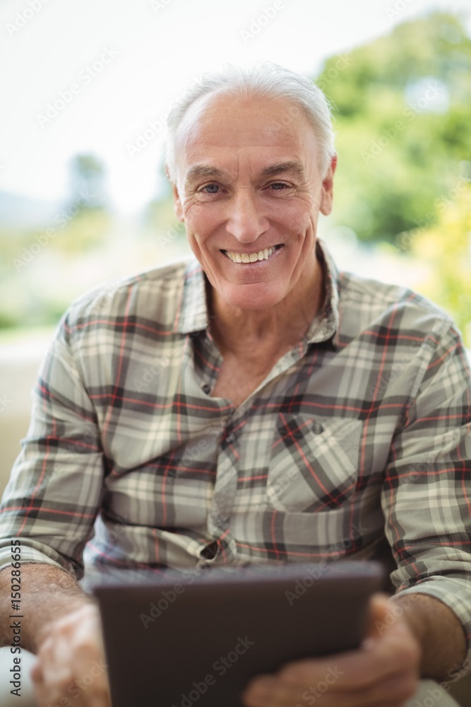 Smiling senior man using digital tablet in living room