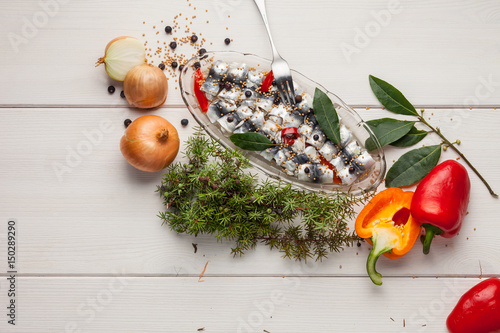 Baltic herring rolls in juniper, paprika and onion marinade. With ingredidients on white wooden background. photo