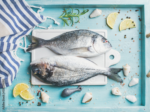Photography Fresh Sea bream or dorado raw uncooked fish with seasoning on white board over t