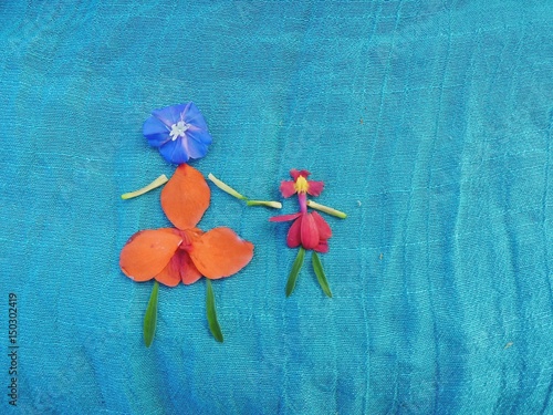 Desenho de mulher e criança montado com delicadas pétalas de flores coloridas sobre  fino tecido azul mar photo