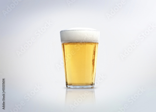 Glass of light lager beer with foam. Isolated on white background.