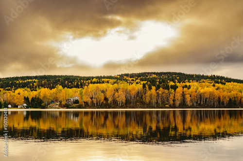 Autumn landscape with foliage colors reflecting on a lake. Cloudy sky.