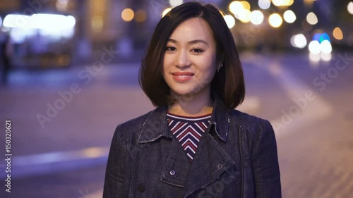 20 year old happy Chinese woman smiles at the camera,in the street atnight photo