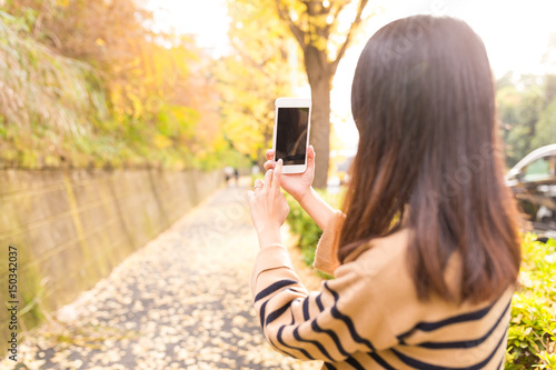 Woman taking photo with cellphone on the autuman landscape photo
