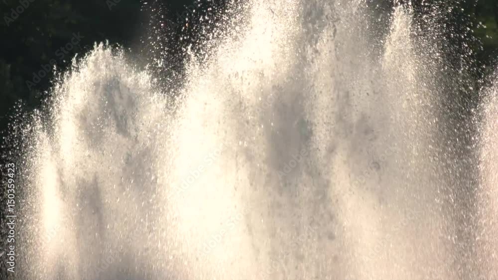 Fountain splashes in motion. Water streams and sunshine.