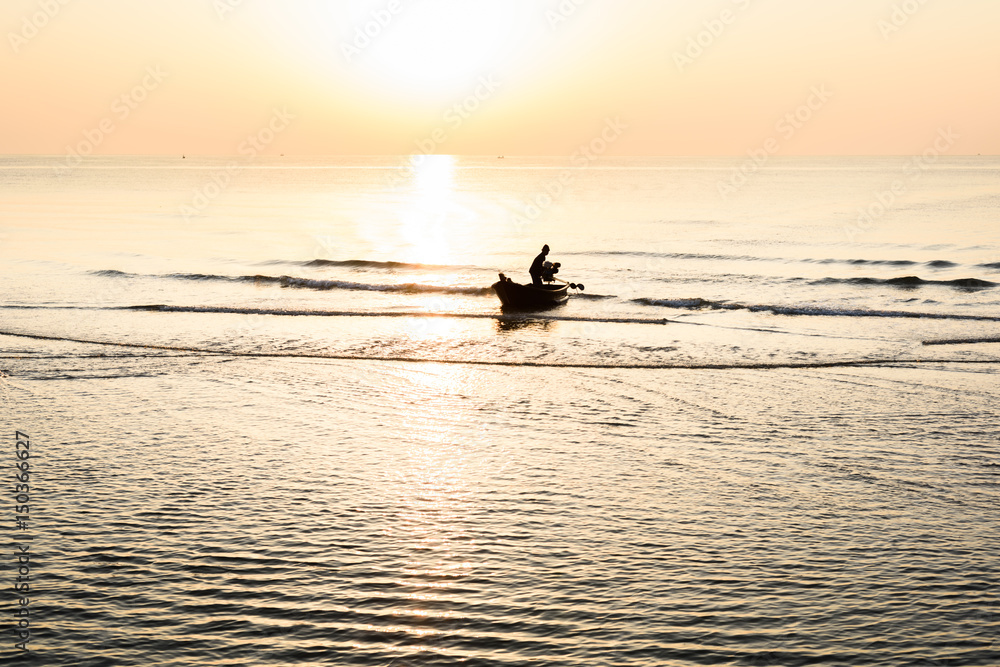 Obraz premium Silhouette of fishing boat and Beautiful tropical sunrise on the beach.