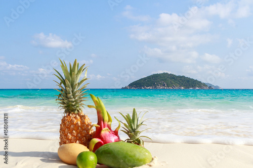 Tropical fruits on the sandy beach against the turquoise sea. Similan Islands, Thailand
