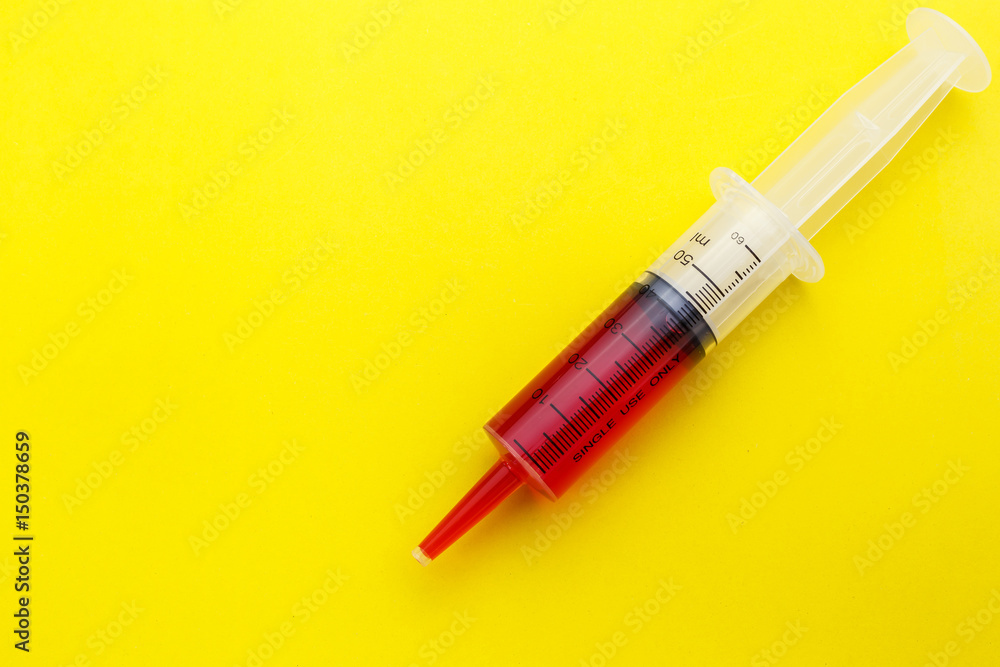 Syringe with red drug on yellow background. Syringe with red drug on yellow background.