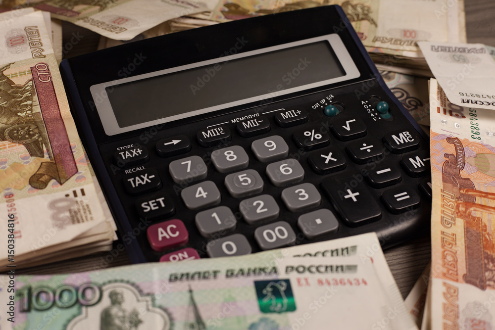 A lot of russian money and calculator on a wooden background. A lot of russian money and calculator on a wooden background.