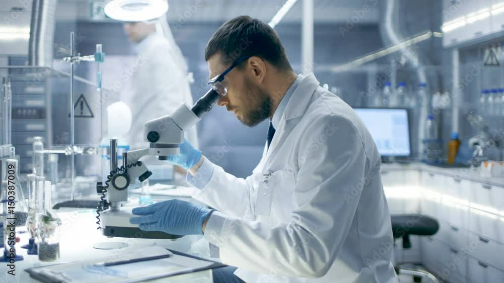 In a Modern Laboratory Research Scientist Experiments With Biological Materials, Uses Microscope and Writes Down Results. Shot on RED EPIC-W 8K Helium Cinema Camera.