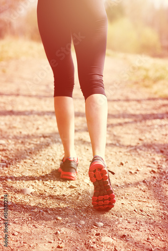 Runner feet running on road closeup on shoe. woman fitness sunrise jog workout welness concept.