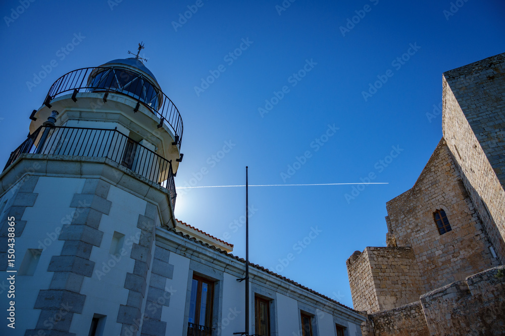 Wide angle backlit of lighthouse and castle