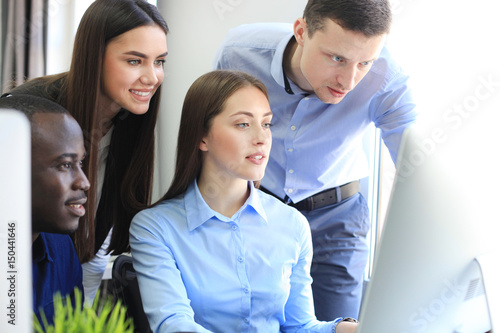 Team of colleagues brainstorming together while working on the computer.