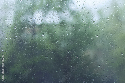 Raindrops on a window glass with trees in the background