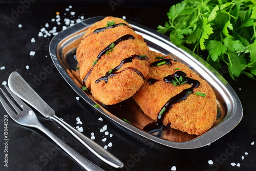 Carrot fritters on a metal plate on a black abstract background. Healthy eating concept photo