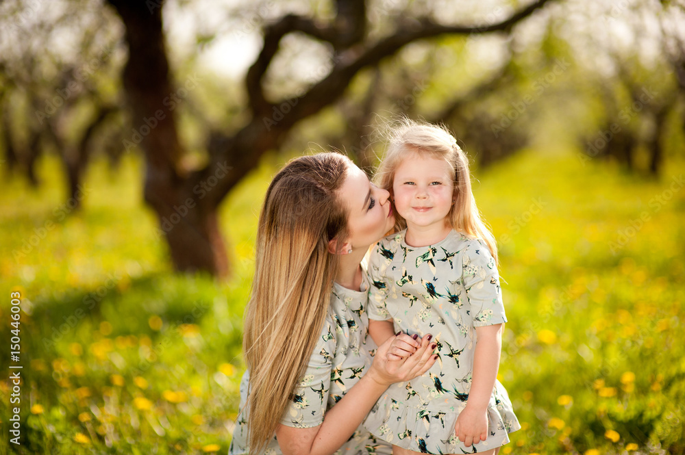 A little girl with her mother on a walk in the spring garden, socialize, laugh, embrace, rejoice, mother and daughter A little girl with her mother on a walk in the spring garden, socialize, laugh, embrace, rejoice, mother and daughter
