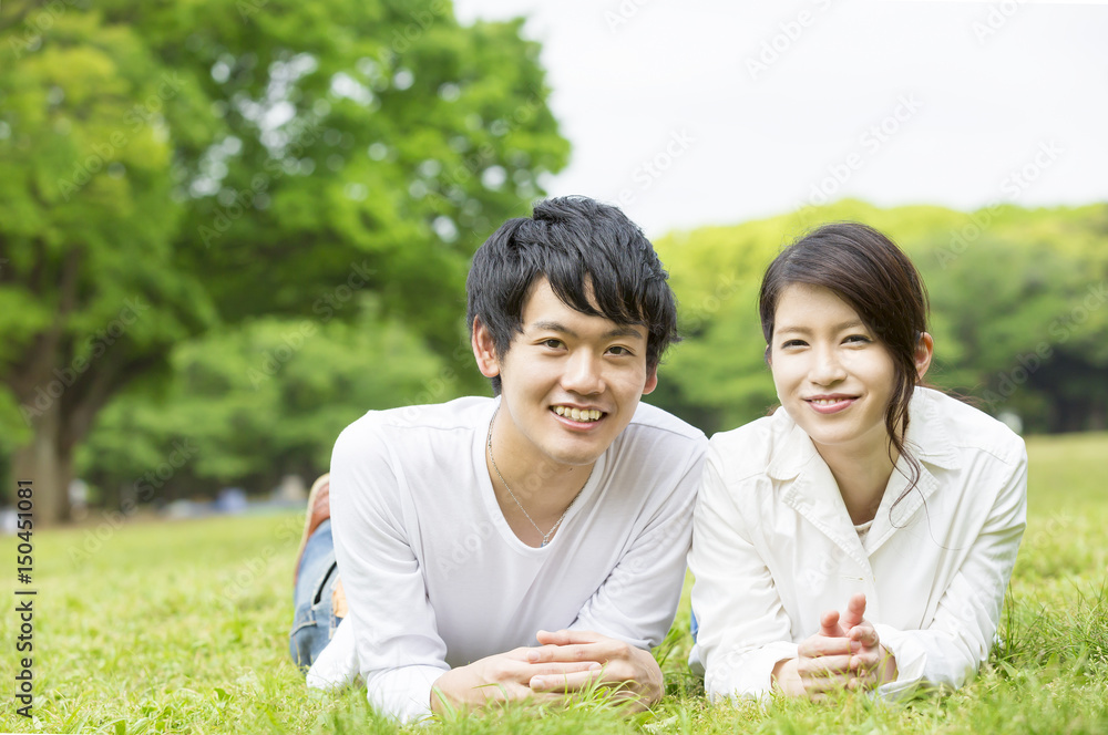 カップル ライフスタイル 新緑の公園の芝生で寝転ぶ カメラ目線 Stock Photo Adobe Stock