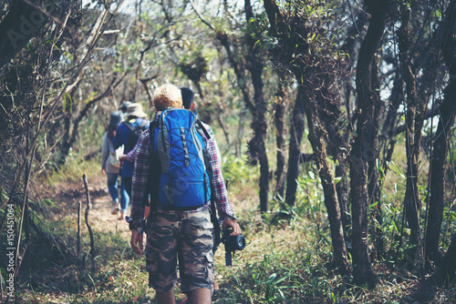 Close up of friends walking with backpacks in woods from back.