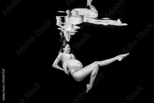 Pregnant woman swimming underwater photo