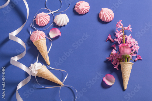 Meringue pie and flowers in a waffle horn on a blue background photo