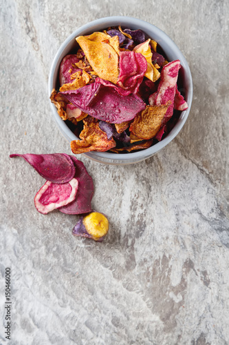 Beet and carrot salty chips in an old blue plate. Stone light background.  Top view