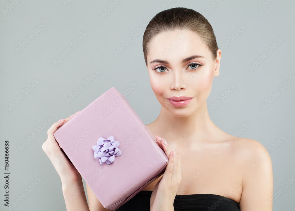 Holiday Concept. Pretty Woman with Perfect Skin and Makeup Holding Gift Box. Smiling Model with Makeup Holiday Concept. Pretty Woman with Perfect Skin and Makeup Holding Gift Box. Smiling Model with Makeup