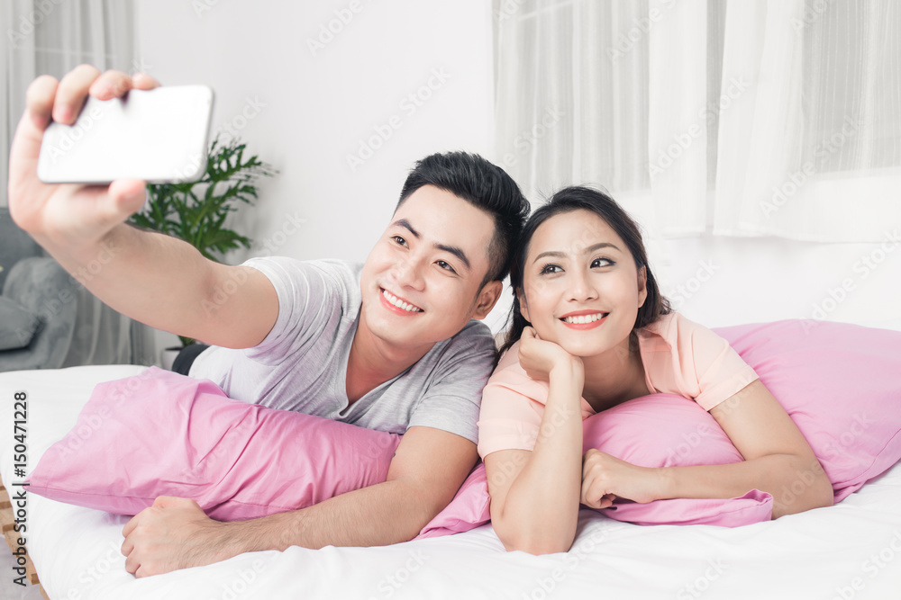Couple taking selfie with phone lying on bed. Couple taking selfie with phone lying on bed.