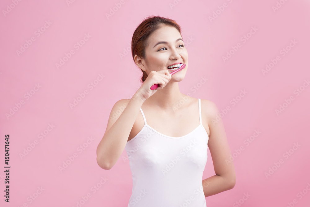 Smiling young woman with healthy teeth holding a tooth brush over pink background. Smiling young woman with healthy teeth holding a tooth brush over pink background.