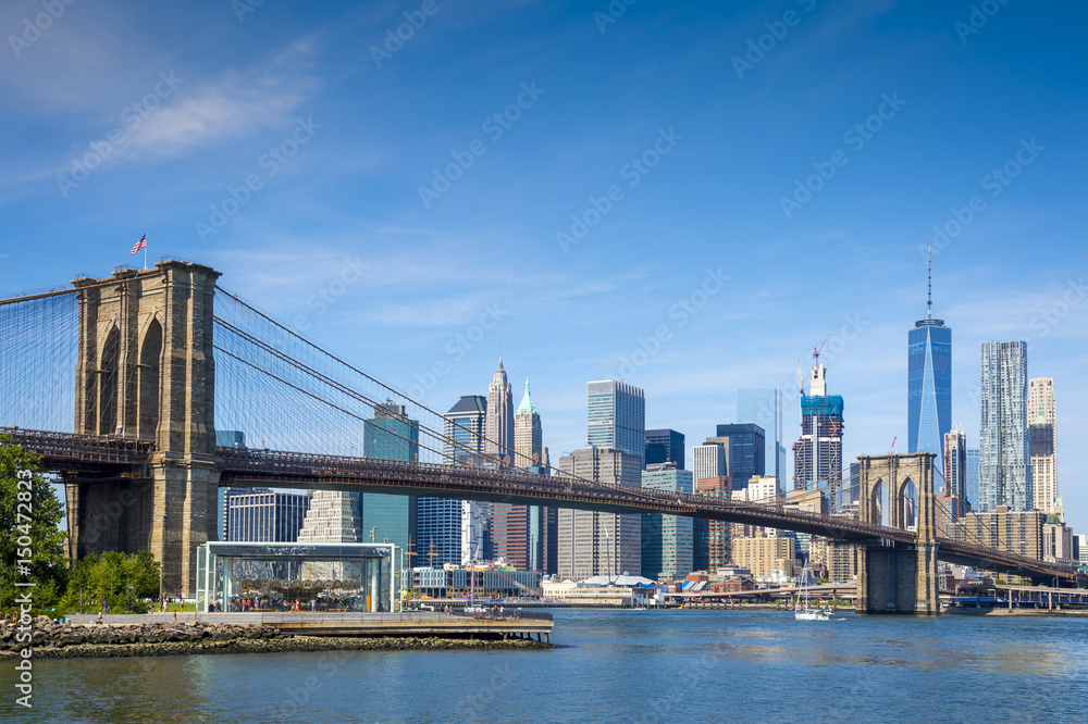 Fototapeta premium Sceniczny widok most brooklyński i lower manhattan linia horyzontu na jaskrawym dniu na Wschodniej rzece w Miasto Nowy Jork