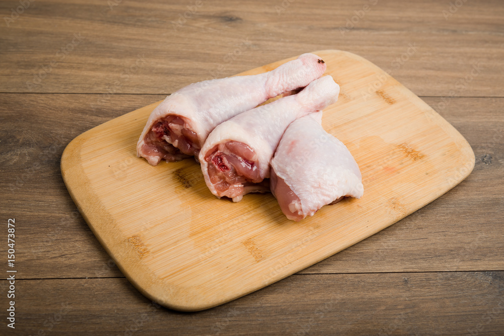 raw chicken legs on wooden board