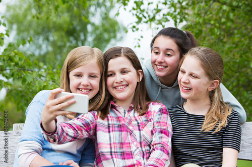 Group Of Young Girls Posing For Selfie In Park