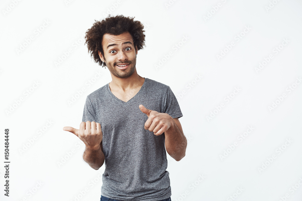 Cheerful african man pointing fingers in side over white background. Copy space. Cheerful african man pointing fingers in side over white background. Copy space.