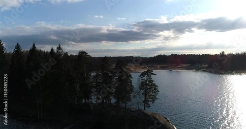 Oittaa, Cinema 4k aerial rising view behind trees revealing Oittaa beach, at bodom lake, on a sunny spring day, in Espoo, Finland photo