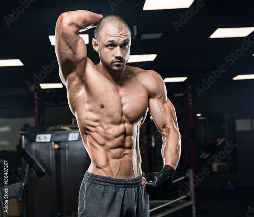 strong and handsome young man doing exercise with dumbbells