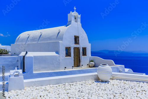 Picturesque view of Old Town of Oia on the island Santorini, white houses, windmills and church with blue domes, Greece