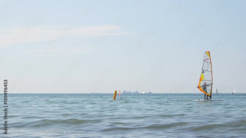 People learn windsurfing on the Baltic Sea in Zelenogradsk. In the background a dry cargo ship. People learn windsurfing on the Baltic Sea in Zelenogradsk. In the background a dry cargo ship.