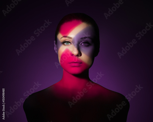 Fashion art portrait of elegant naked young woman with color light on her face