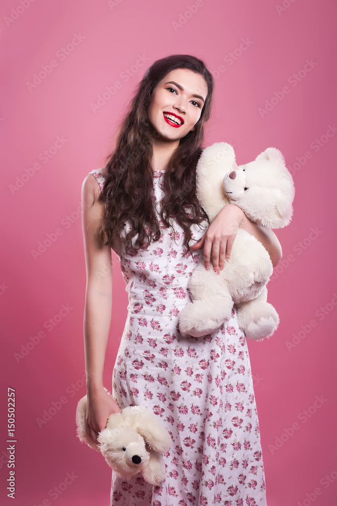 Beautiful girl holds two toy bears on a pink background Beautiful girl holds two toy bears on a pink background