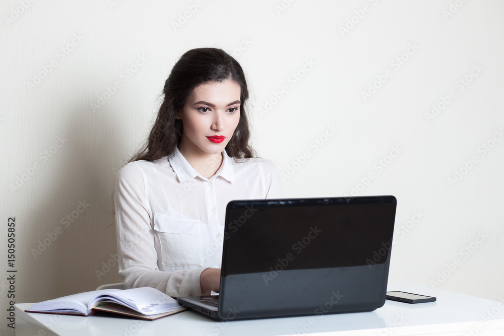 Young beautiful girl working at the computer on a white background Young beautiful girl working at the computer on a white background