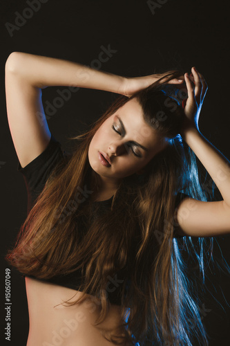 Glamorous woman with long brunette hair and bright makeup posing at studio