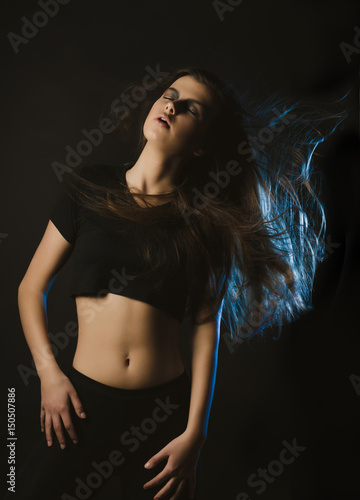 Sensual young woman with fluttering hair posing at studio with blue light © vpavlyuk