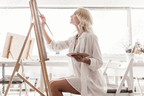 Foto Morning, the artist sits on a chair, painting a picture and holding a brush